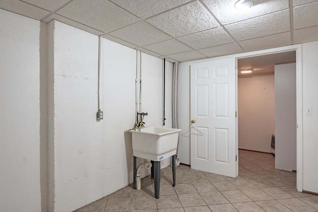 finished basement featuring light tile patterned floors and a drop ceiling