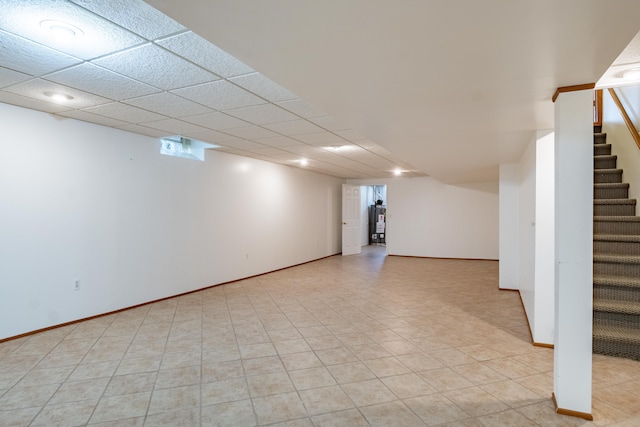 finished below grade area featuring stairs, water heater, and baseboards