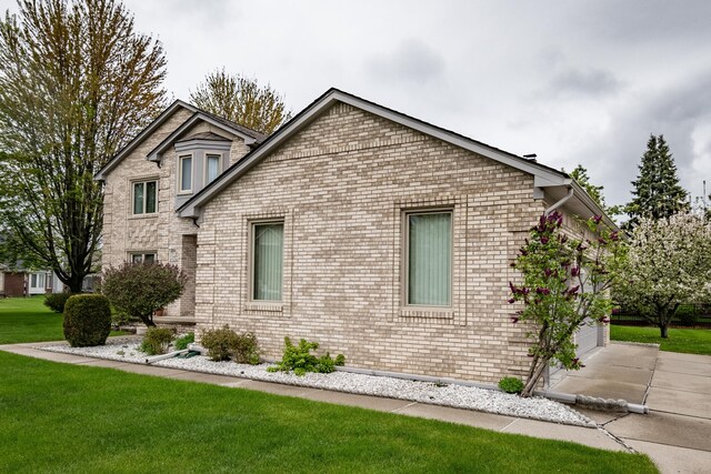 view of home's exterior featuring a lawn, brick siding, a garage, and concrete driveway