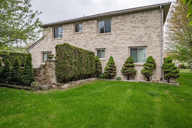 back of property with a lawn and brick siding