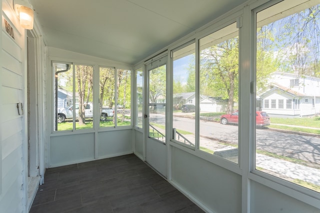 unfurnished sunroom with lofted ceiling, plenty of natural light, and a residential view