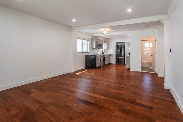 unfurnished living room featuring crown molding, dark wood-style floors, baseboards, a sink, and recessed lighting