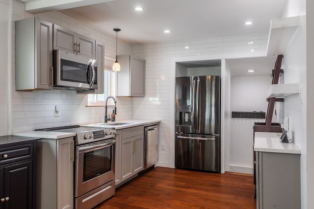 kitchen featuring stainless steel appliances, gray cabinetry, a sink, light countertops, and dark wood-style flooring