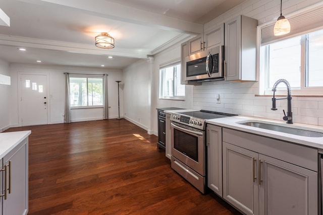kitchen featuring appliances with stainless steel finishes, gray cabinetry, a sink, beam ceiling, and decorative backsplash