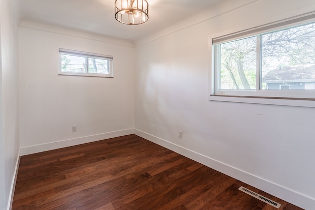 unfurnished room with baseboards, dark wood-type flooring, and a chandelier