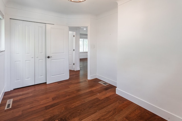 unfurnished bedroom featuring baseboards, dark wood finished floors, and a closet