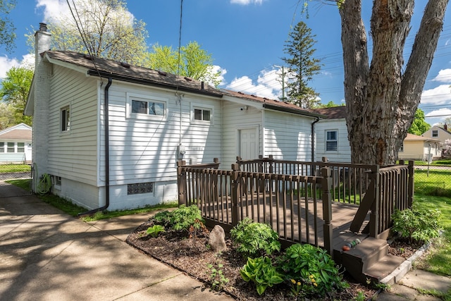 rear view of property featuring a chimney, a wooden deck, and fence