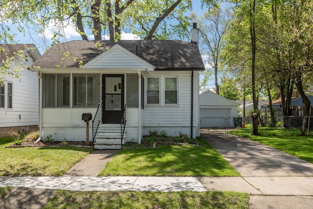 bungalow-style house featuring a garage, a chimney, roof with shingles, an outdoor structure, and a sunroom