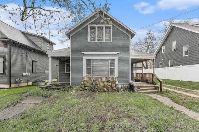 view of front of house featuring a porch, a front lawn, and fence