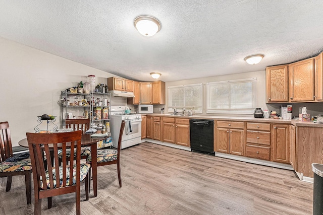 kitchen with a sink, white appliances, a textured ceiling, under cabinet range hood, and light wood-style floors