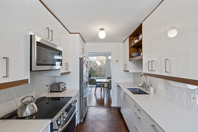 kitchen featuring appliances with stainless steel finishes, a sink, open shelves, decorative backsplash, and white cabinets