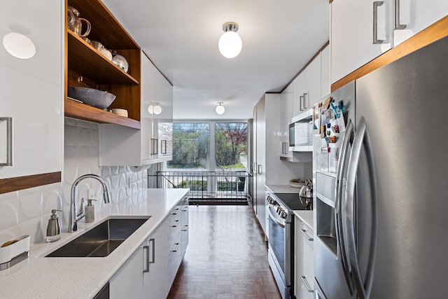 kitchen featuring a sink, stainless steel appliances, open shelves, white cabinetry, and modern cabinets