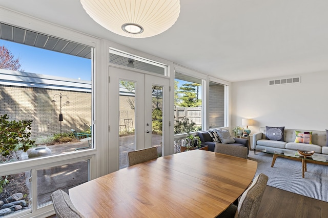 dining room featuring a wall of windows, french doors, visible vents, and wood finished floors