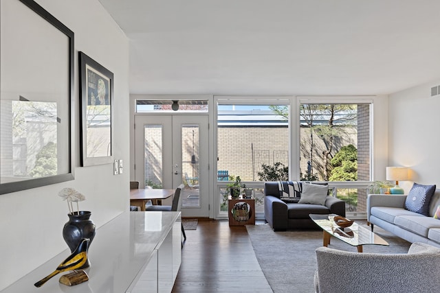 living area with a wall of windows, visible vents, and dark wood-type flooring