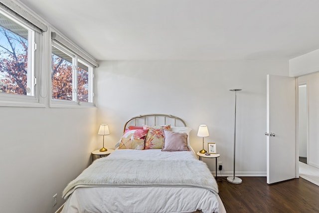 bedroom with baseboards, multiple windows, and wood finished floors