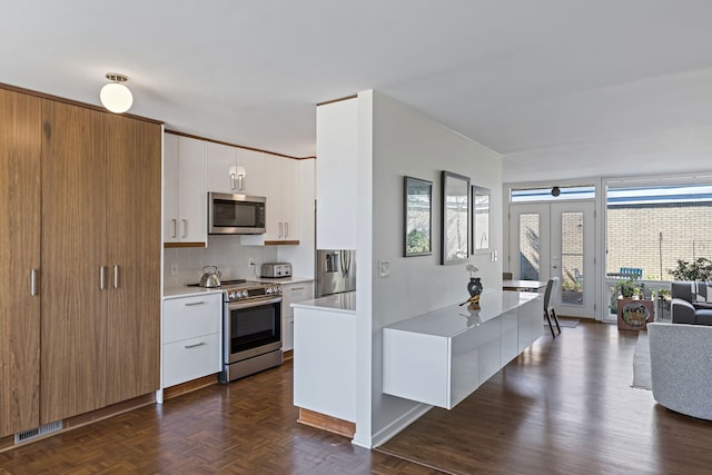 kitchen with stainless steel appliances, visible vents, white cabinetry, light countertops, and tasteful backsplash