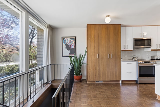 kitchen featuring stainless steel appliances, a toaster, decorative backsplash, light countertops, and white cabinets