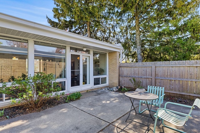 view of patio / terrace featuring fence, a sunroom, and outdoor dining area