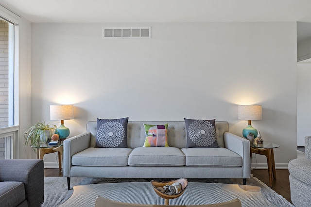 living area with baseboards, visible vents, and wood finished floors