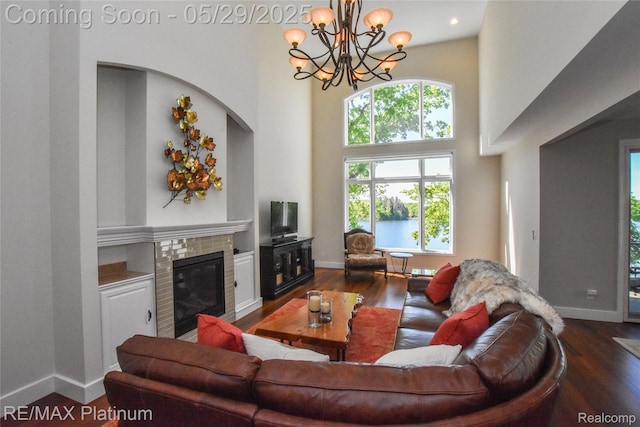 841 Hurley Dr, Howell, MI 48843 - living area featuring a tiled fireplace, wood finished floors, baseboards, a towering ceiling, and a chandelier