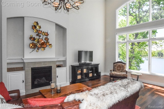 841 Hurley Dr, Howell, MI 48843 - living area featuring a chandelier, a brick fireplace, arched walkways, a towering ceiling, and wood finished floors