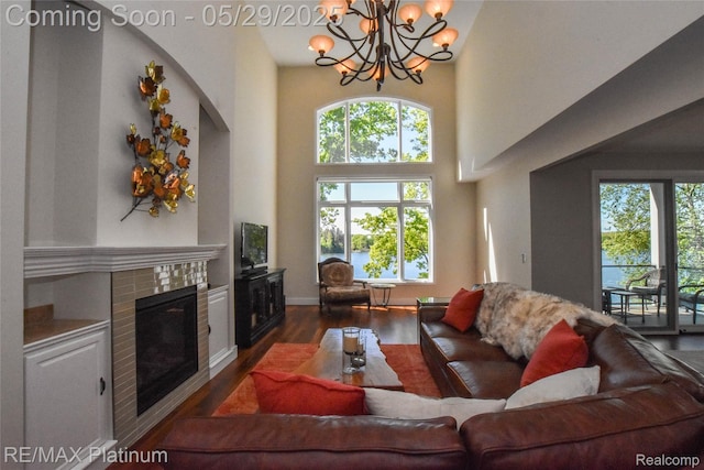 841 Hurley Dr, Howell, MI 48843 - living area with dark wood-type flooring, healthy amount of natural light, a towering ceiling, a chandelier, and a tile fireplace