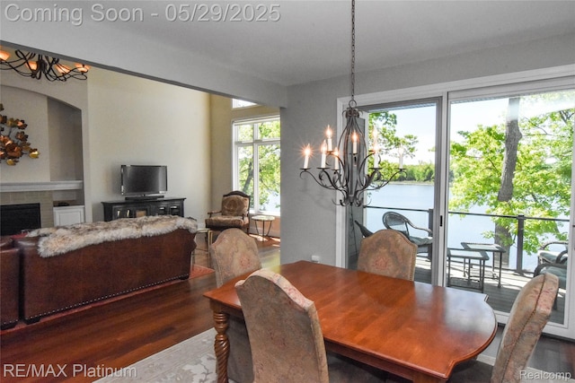 841 Hurley Dr, Howell, MI 48843 - dining room with wood finished floors, a chandelier, a tiled fireplace, and built in shelves