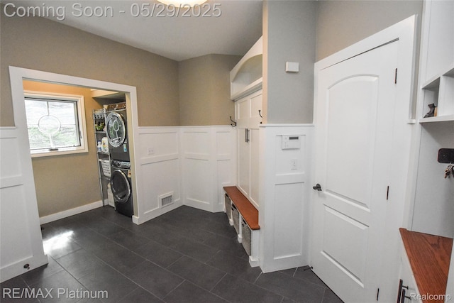 841 Hurley Dr, Howell, MI 48843 - washroom with stacked washer and clothes dryer, dark tile patterned flooring, and wainscoting