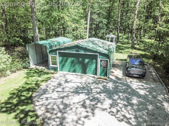 841 Hurley Dr, Howell, MI 48843 - garage featuring a detached carport, a wooded view, and driveway