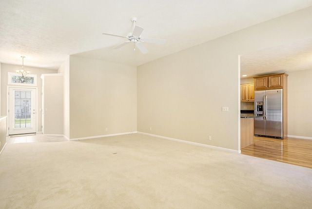 unfurnished living room with baseboards, light colored carpet, and ceiling fan with notable chandelier