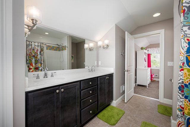 bathroom featuring double vanity, a sink, tile patterned floors, visible vents, and lofted ceiling