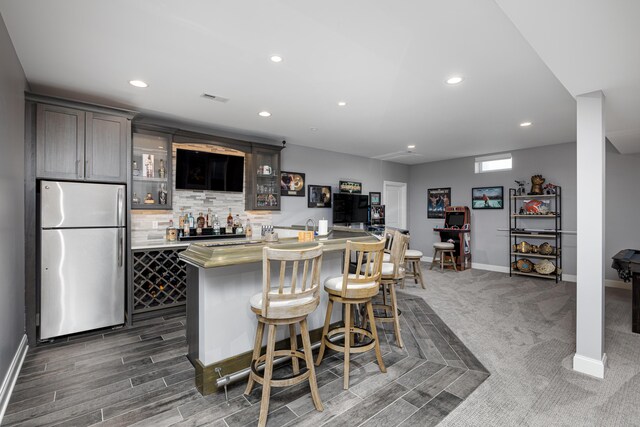bar featuring freestanding refrigerator, indoor bar, visible vents, and recessed lighting