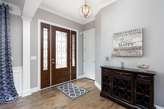 foyer featuring baseboards, a notable chandelier, crown molding, and wood finished floors