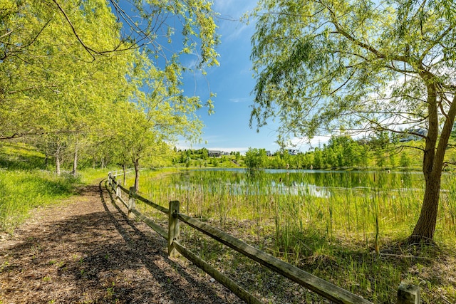 view of yard with a wooded view, a water view, and fence