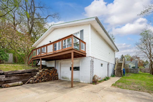 view of side of property with an attached garage, driveway, a deck, and stairs