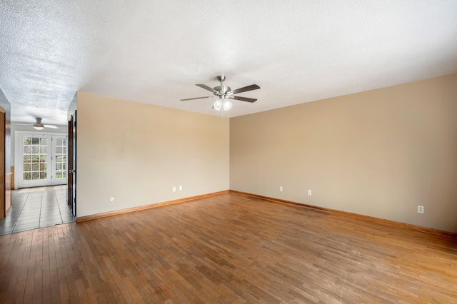 spare room with baseboards, light wood-style floors, ceiling fan, and a textured ceiling