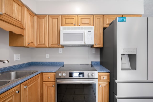 kitchen with white appliances, dark countertops, and a sink