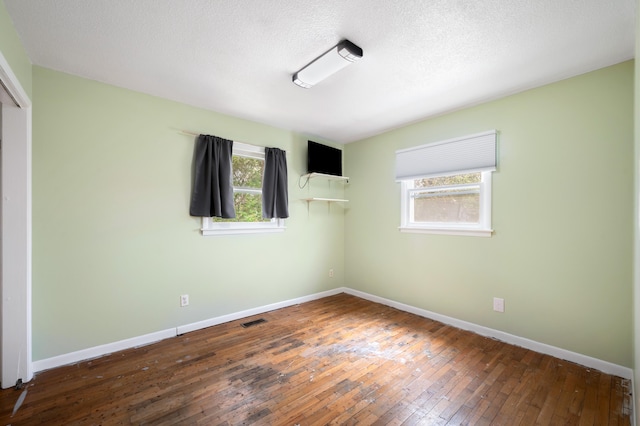 unfurnished bedroom with a closet, a textured ceiling, baseboards, visible vents, and wood-type flooring