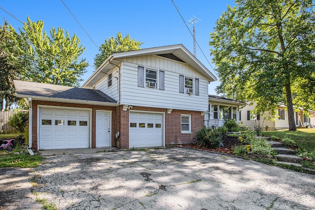 tri-level home featuring board and batten siding, a garage, brick siding, and driveway