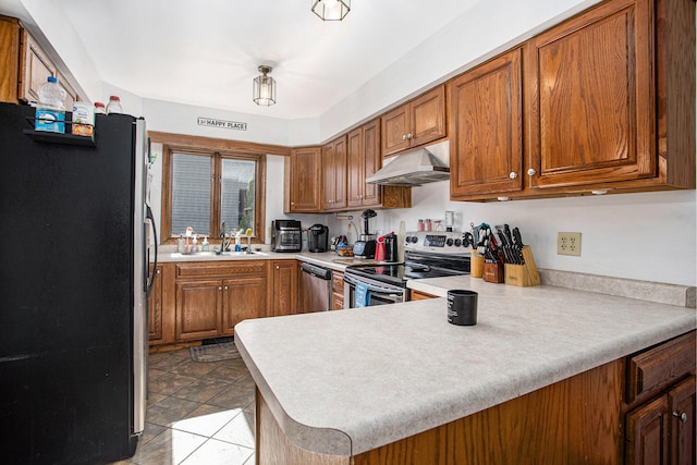 kitchen with a sink, brown cabinetry, under cabinet range hood, light countertops, and appliances with stainless steel finishes