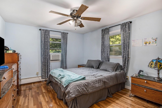 bedroom with cooling unit, multiple windows, wood finished floors, and ceiling fan