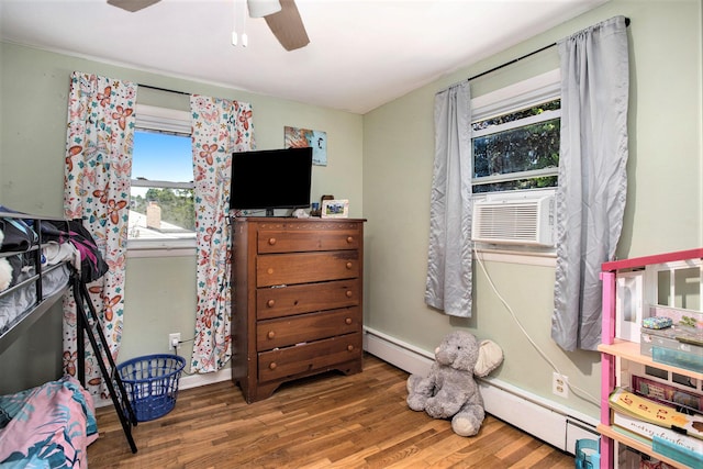 bedroom featuring a baseboard heating unit, cooling unit, baseboards, ceiling fan, and wood finished floors