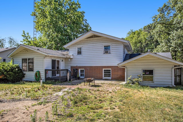 back of property with a lawn, brick siding, a fire pit, a wooden deck, and roof with shingles