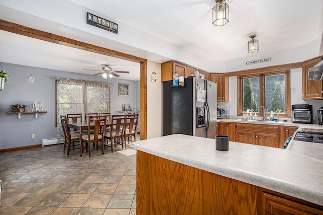 kitchen with brown cabinetry, baseboards, stainless steel fridge with ice dispenser, and a sink
