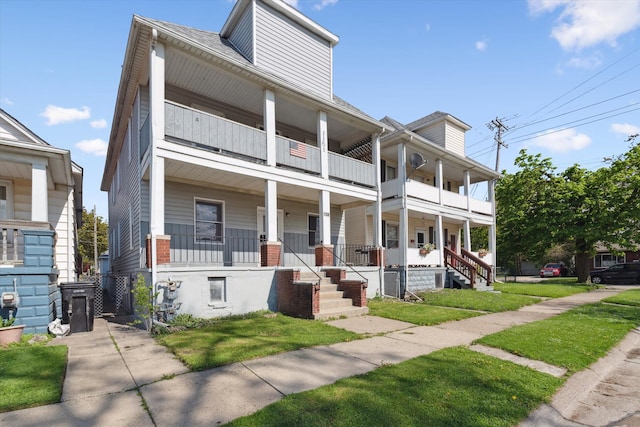 townhome / multi-family property with a balcony, a porch, and a front lawn