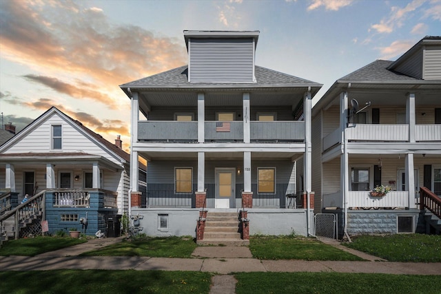 multi unit property with a porch, roof with shingles, and a balcony