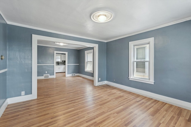 unfurnished room featuring baseboards, ornamental molding, visible vents, and light wood-type flooring