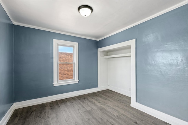 unfurnished bedroom with baseboards, a closet, crown molding, and wood finished floors