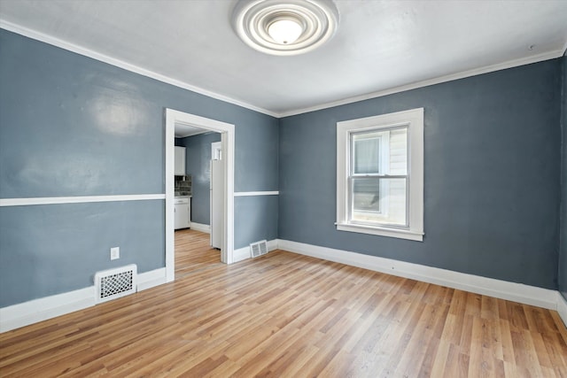 unfurnished room featuring wood finished floors, visible vents, baseboards, and ornamental molding