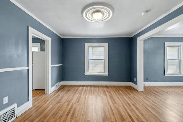 interior space with visible vents, wood finished floors, baseboards, and ornamental molding